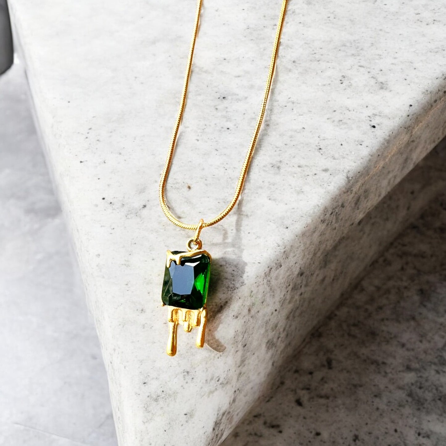 Necklace with a green gemstone pendant on a marble surface
