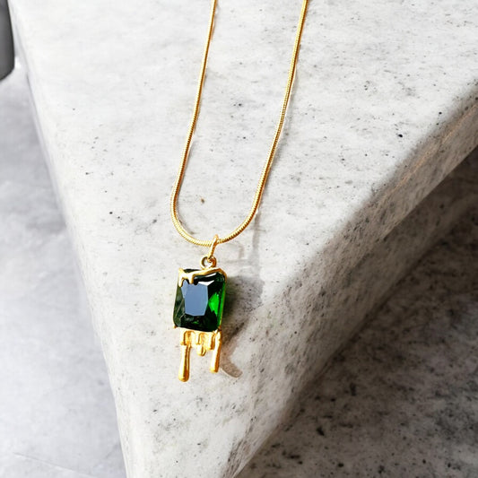 Necklace with a green gemstone pendant on a marble surface