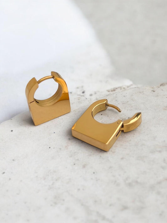 Gold hoop earrings on a light gray surface
