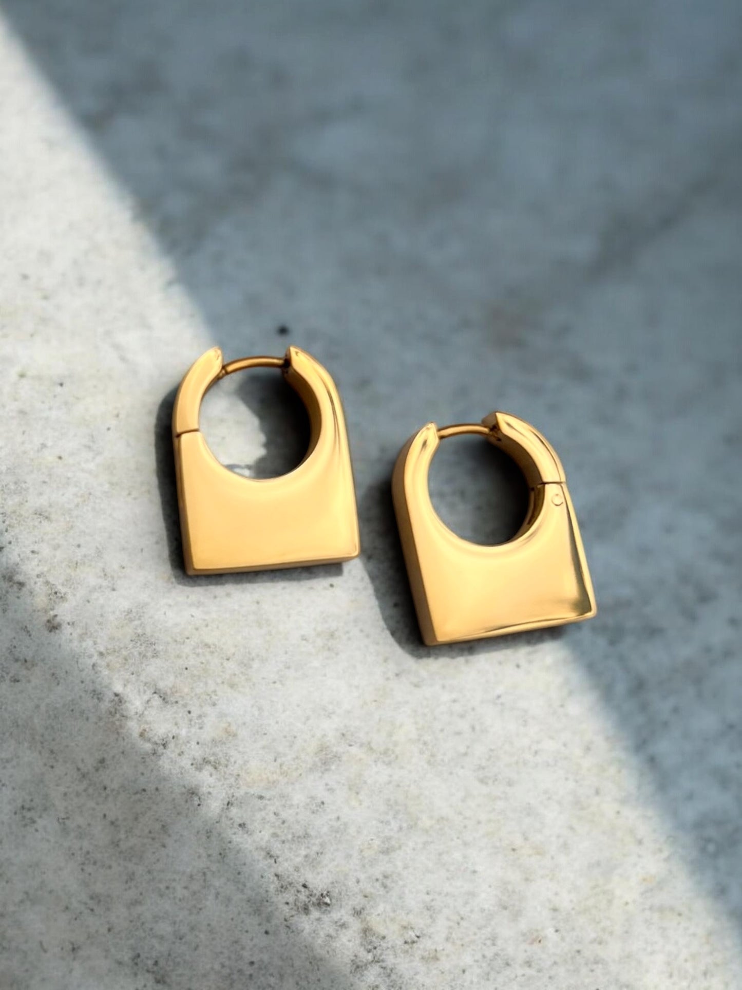 Gold hoop earrings on a textured gray surface